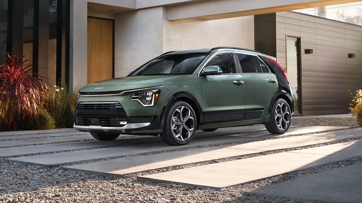 Kia Niro hybride vert forêt stationné devant une maison contemporaine, mettant en valeur son design urbain et écologique.